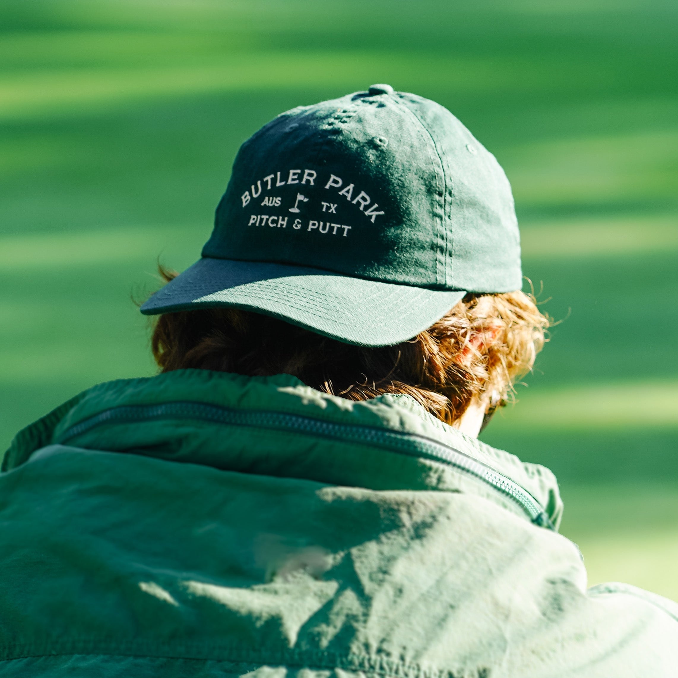 The Butler Dad Hat in forest green worn backwards.